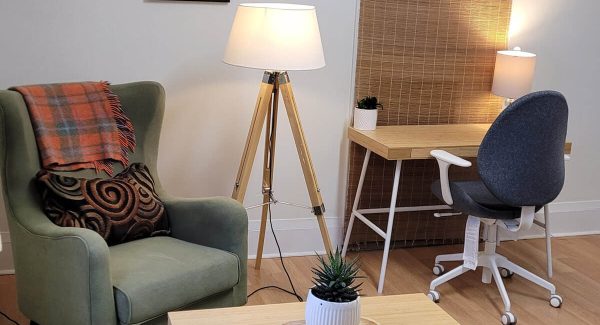 Wing back chair, lamo, coffee table with plant and office desk.